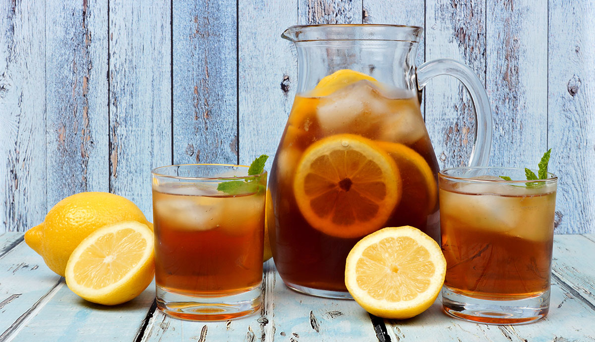 Pitcher of iced fruit tea with two glasses on rustic blue wood