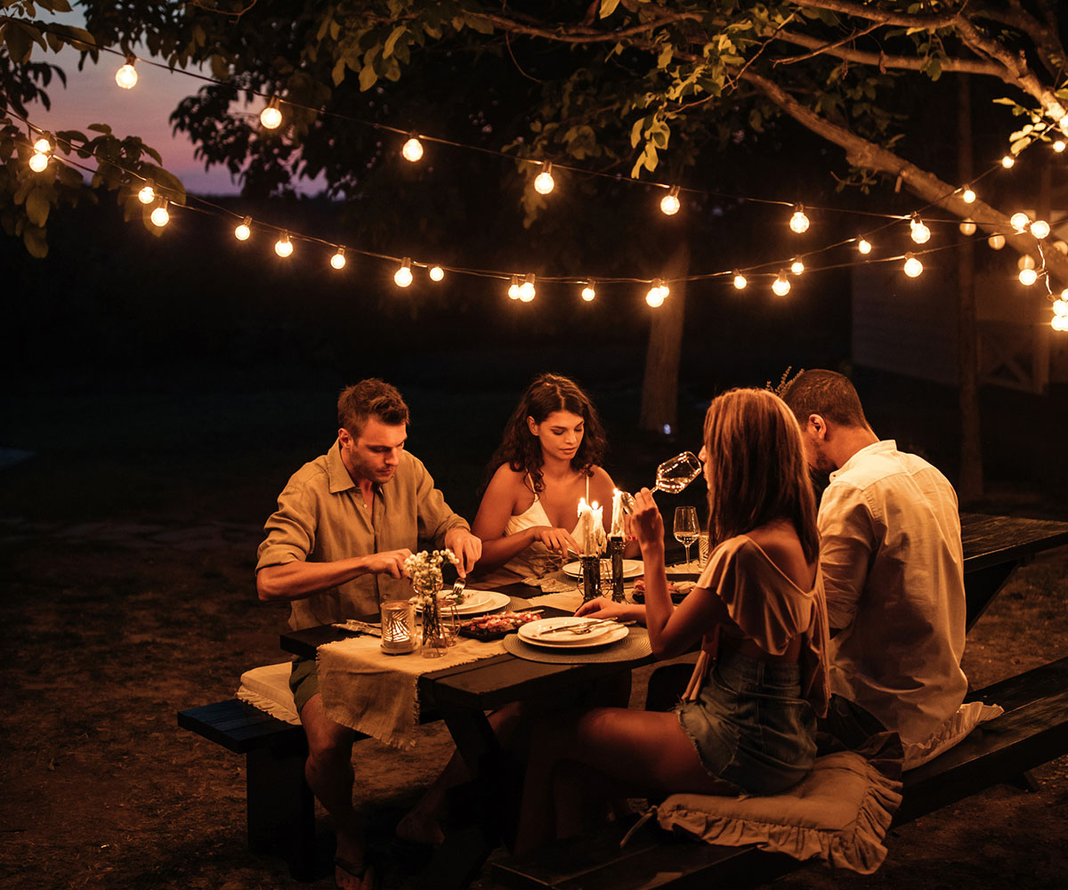 Two couples having a dinner party in a backyard