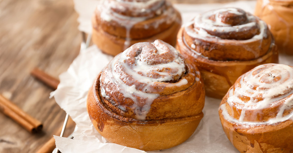 Cooling rack with cinnamon rolls on wooden table