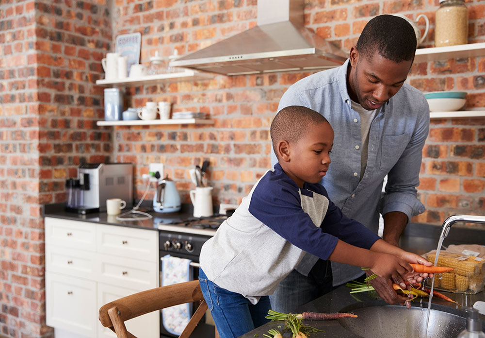 Boy helping dad wash vegetables