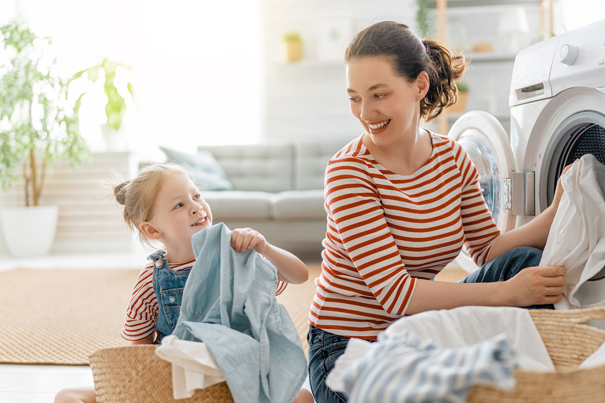 girl helping mom fold laundry